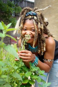 Photo of Rosie Warren, a young black woman with a pot of herbs